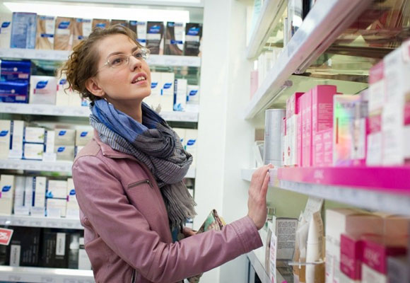 Женщина ищект лекарство на полке в аптеке